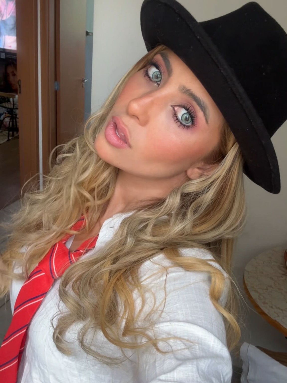 Jessy Portilla como Mia Colucci, farda escolar com gravata e chapéu